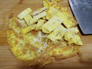 白玉菇鸡蛋汤,这时将煎好的蛋片放在案板上。用刀切条，大小随意。