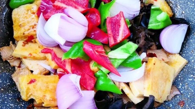 干锅千叶豆腐,然后放入青椒，红椒，葱头，木耳，大火翻炒