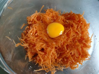 炸胡萝卜丸子,将萝卜丝放入盆中，打入一个鸡蛋。