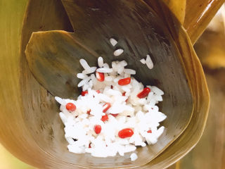 红豆粽子,拿两片粽叶，毛面向下卷成锥形，放入一勺糯米