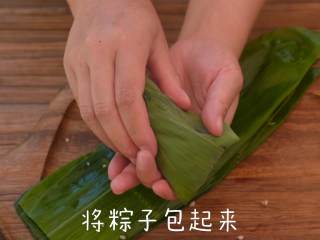 香甜的红糖蜜枣粽,将粽叶的两端保持交叠，反向折回盖在糯米上，且一定要压紧实。