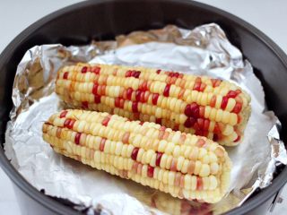 风味烤玉米,康佳空气炸锅的炸篮底下铺上一层锡纸，把煮熟的玉米码放在上面。