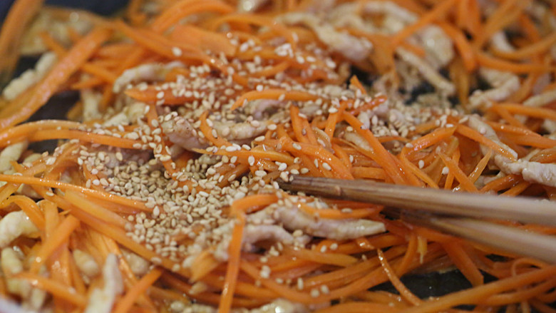 胡萝卜炒肉丝,加入白芝麻拌均匀，装盘撒上葱花上桌。