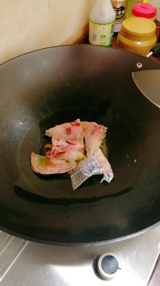 特色鱼头豆腐汤,鱼头鱼骨放入油中煎香至两面金黄