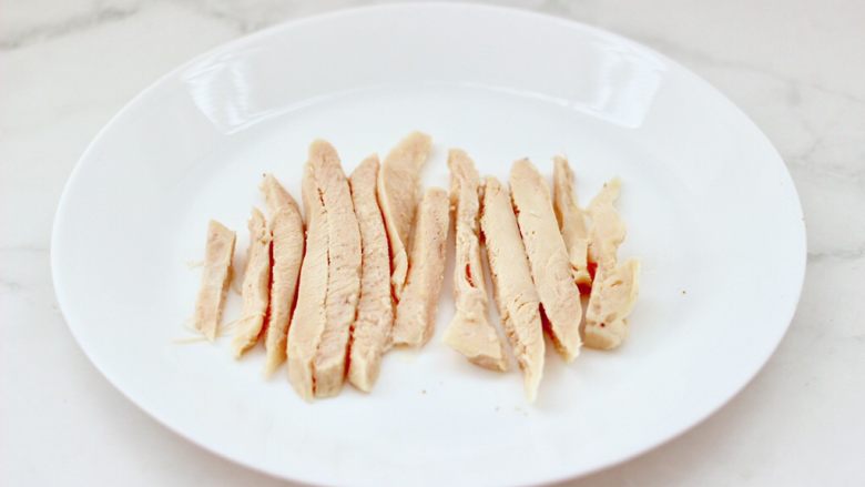 风味酸黄瓜鸡肉热压三明治,把加热好的鸡胸肉，用刀切成粗条。