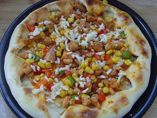 新奥尔良风味鸡肉披萨,将鸡丁馅料均匀的放在饼上，馅料之间适量的撒上奶酪丝