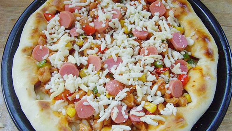 新奥尔良风味鸡肉披萨,点缀上烤肠片，剩余的芝士丝全部均匀的撒在馅料上