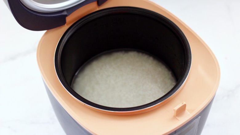 花肉土豆焖饭,浸泡好的大米洗净后，倒入康佳电饭煲里，倒入适量的清水。
