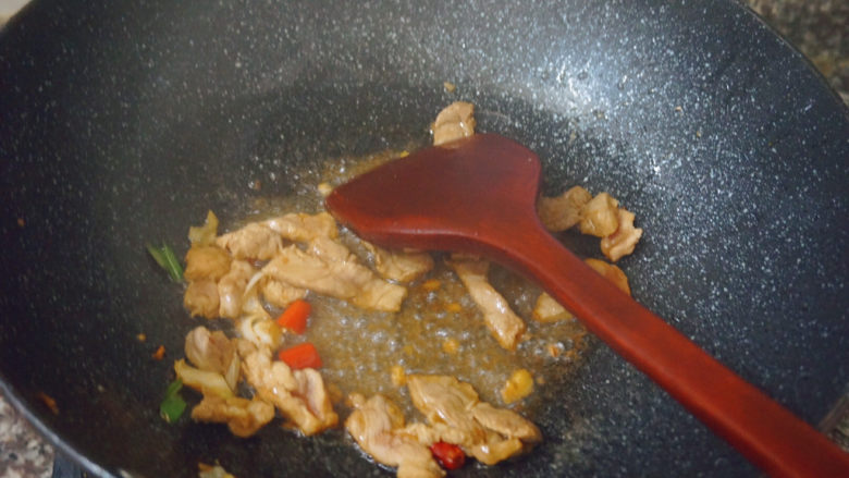 四季豆炒肉,锅内热油下锅，倒入蒜泥和红米椒翻炒肉片