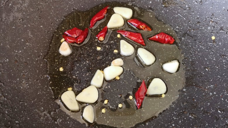 白玉菇炒肉,炒锅内继续倒油烧热，下入蒜片和干红辣椒炒香。