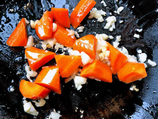 丝瓜花蛤汤,锅中倒入底油放入蒜粒爆香再放入胡萝卜块炒至断生
