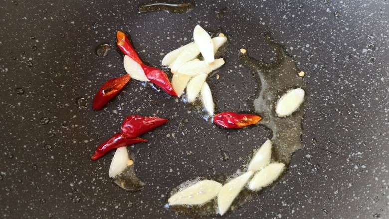 黄瓜炒香肠,炒锅内继续倒油烧热，下入蒜片和干红辣椒炒香。