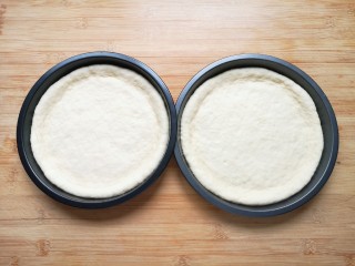 培根火腿披萨,发酵好的面团揉光排气，分成两份再次揉光，擀成和模具大小一致的面饼，放进披萨盘里。