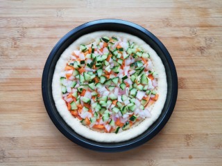 培根火腿披萨,撒上胡萝卜、黄瓜和洋葱小丁。