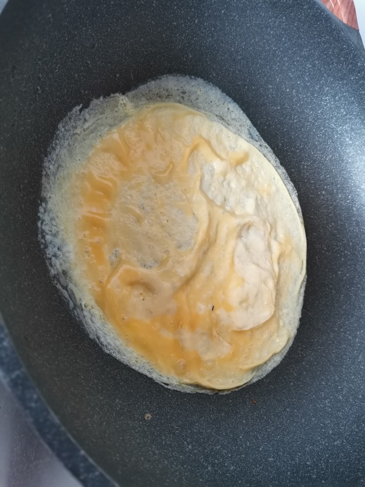 莴笋炒鸡蛋,晃动锅，让蛋液摊成一个圆饼。
