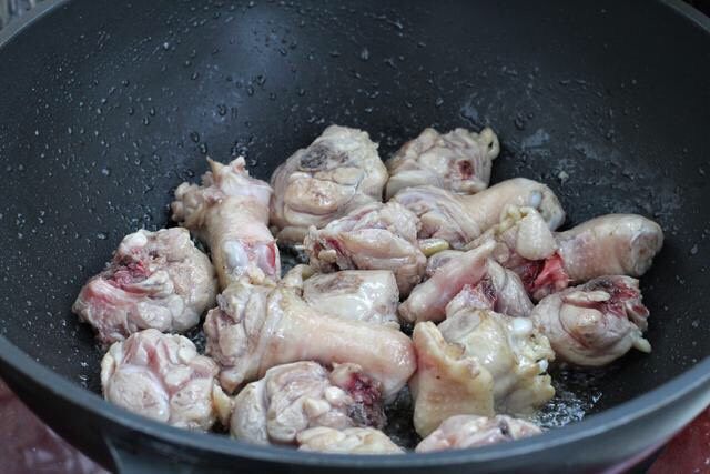 香菇焖鸡,锅中倒食用油烧热，放入鸡腿肉翻炒至变色断生状态。