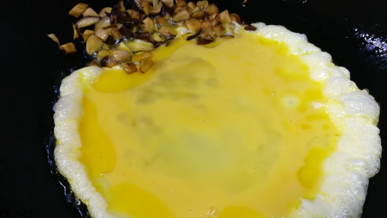 香肠炒蛋,把香菇丁推到锅的一边，倒入蛋液。