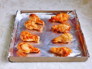 新奥尔良烤鸡腿,腌制好的鸡腿摆放在垫好锡纸的烤盘中。