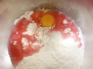 蝴蝶结面包,红曲精华滴入装有清水的量杯中。和面粉、酵母粉、白糖、鸡蛋一起放入和面机中。