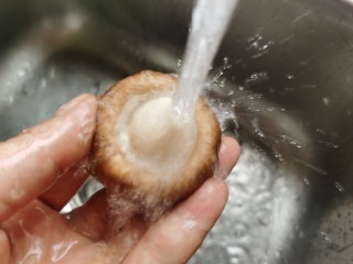 孜然烤香菇,将香菇逐个在水龙头下冲洗干净，不要把香菇一起全部泡到盆里清洗，那样香菇会吸收过多的水分，烤起来比较费时间。