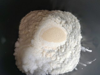 淡奶油甜面包,接下来加入高筋面粉，糖和盐对角放，面粉中间挖个小洞放入干酵母，用面粉盖上，选择面包机的“自动和面”程序15分钟。