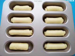 黄油面包卷,将面包卷生胚放入模具里面（没有模具也可以直接放在不粘烤盘或者铺了油纸的普通烤盘里）。