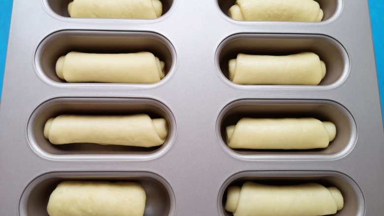 黄油面包卷,将面包卷生胚放入模具里面（没有模具也可以直接放在不粘烤盘或者铺了油纸的普通烤盘里）。