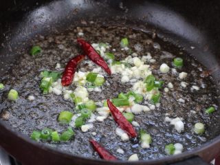 醋溜豆芽,就着锅中底油放入葱花、姜、蒜末和红干椒，小火煸炒出香味。