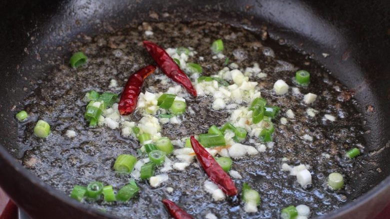 醋溜豆芽,就着锅中底油放入葱花、姜、蒜末和红干椒，小火煸炒出香味。
