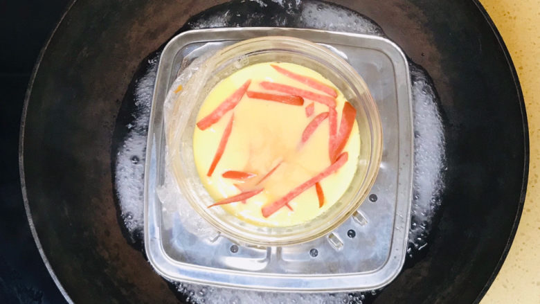 腊肠蒸蛋,一直煮至鸡蛋液八成凝固时，将剩下的香肠丝加入鸡蛋液表面