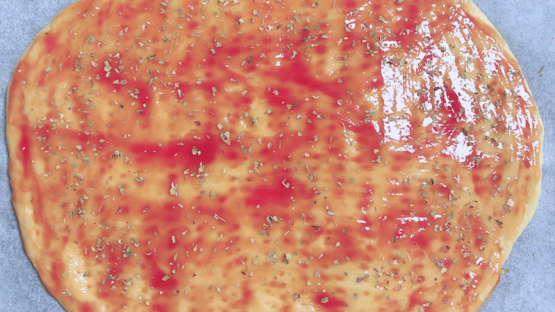 黑椒牛肉披萨,在饼上刷一层番茄沙司，撒上一层披萨草。