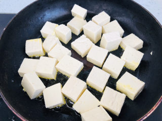香菇肉末豆腐,平底不粘锅倒入适量食用油，放入切好的豆腐，中小火煎至两面金黄色。