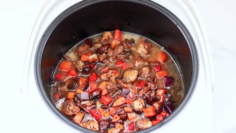 懒人版鸡翅香菇焖饭,上面倒入炒熟的食材，把泡发香菇的水倒入。