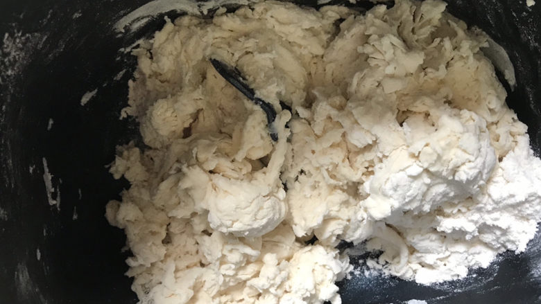 紫薯玫瑰花馒头,白色面团，称好面粉，酵母，水在面包桶里，搅拌至絮状，放入面包机启动和面程序