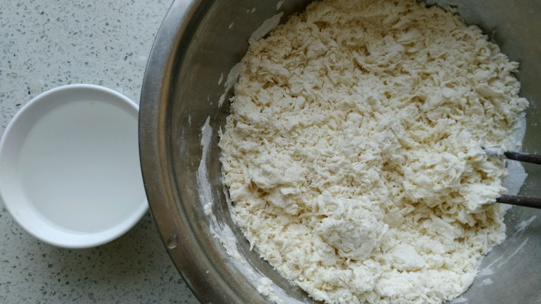椒盐小花卷,把酵母水全部倒入面粉中，先用筷子搅拌均匀成棉絮状，另外再准备一碗温水。
