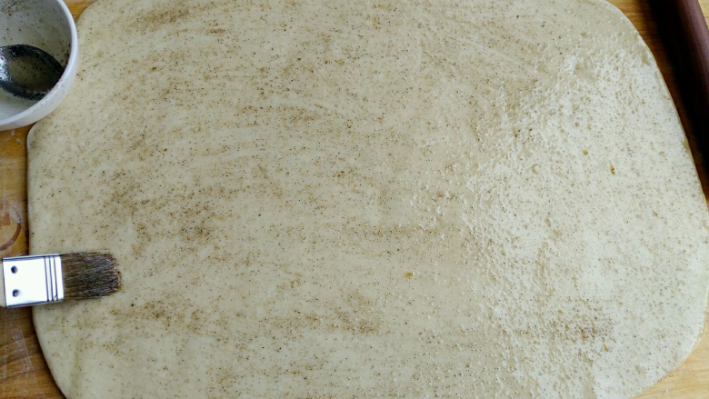 椒盐小花卷,面团擀成厚度约5毫米的大长方形，淋上椒盐油，用刷子刷开抹匀。