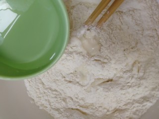 糖火烧,温水加入面粉里，筷子边加边搅拌。