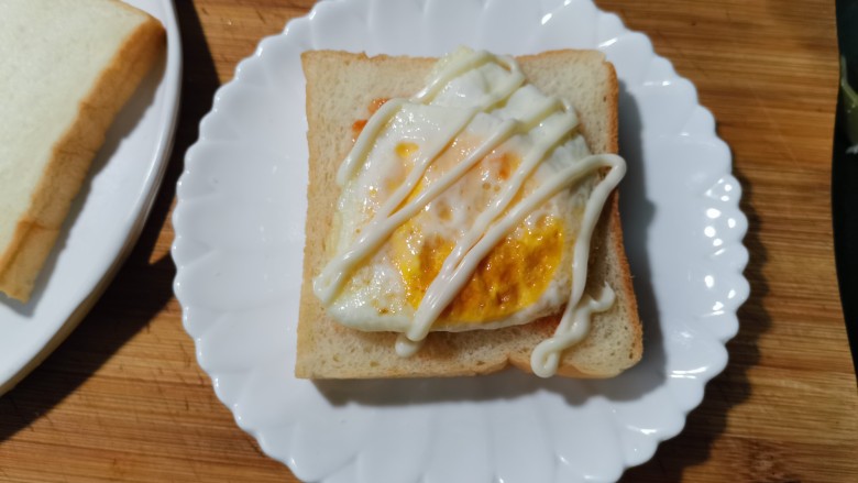 芝士火腿三明治,取一片吐司放上沙酱或西红柿酱。放上煎好的蛋。
