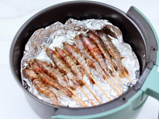 孜然风味烤虾,依次串完所有腌制好的虾，空气炸锅提前200度预热5分钟后，把串好的虾放入炸篮里。