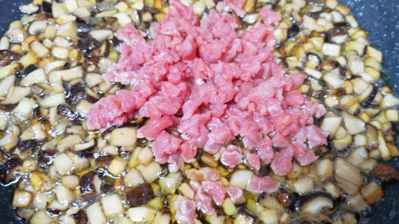 香菇牛肉酱,杏鲍菇和香菇炸至体积明显变小的时候下入牛肉粒翻炒均匀。

