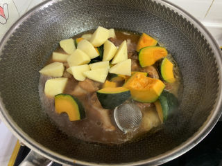 鸡翅根炖土豆南瓜,15分钟后加入切好的南瓜和土豆块。