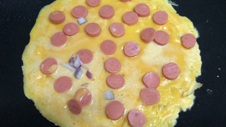 鸡蛋饼披萨,趁鸡蛋糊还没有凝固，铺上火腿片。
