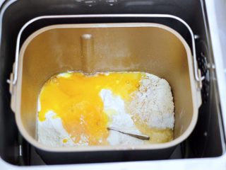 妈妈的味道～花式花样果子,把称重的食材倒入面包机里，鸡蛋打散加入白糖，开始启动和面模式。
