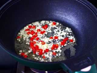 辣爆鸡丁秋葵,锅中倒入花生油烧热后，爆香小米辣和大蒜。