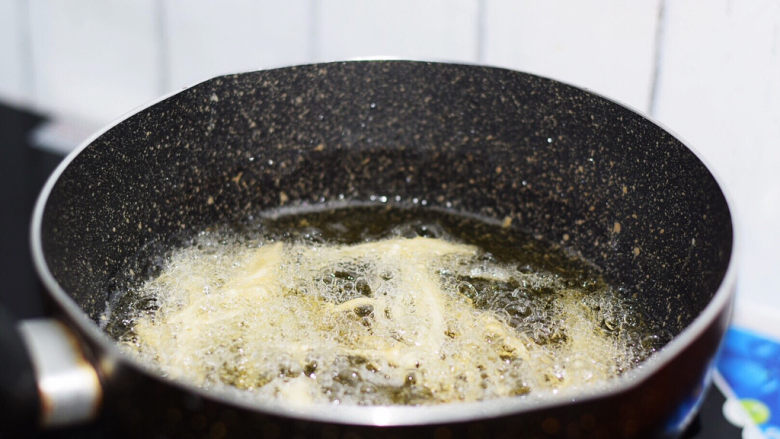 油炸金针菇,锅中倒入适量的食用油烧至6成热，放入金针菇炸3分钟定型后