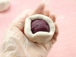 紫薯芝麻饼,取一个小面团用手按压成饼皮，放上紫薯馅包裹起来，收口封严。