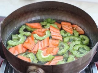 苦瓜炒虾仁,取一个小锅添适量清水烧开，放入苦瓜和胡萝卜焯烫约一分钟，捞出过凉水沥干水分备用。
