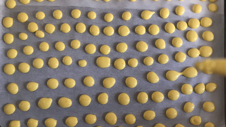 宝宝蛋黄溶豆,然后挤入铺了油纸的烤盘，每两个溶豆之前间隔一个溶豆的距离