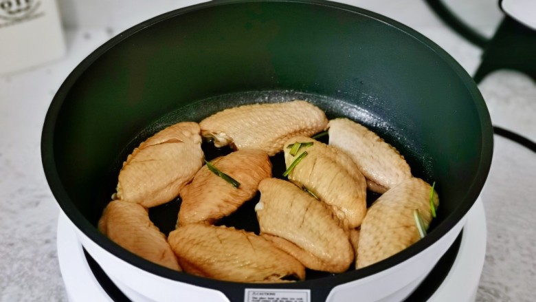 干锅麻辣鸡翅,不粘锅中刷上少许食用油，再摆上鸡翅。