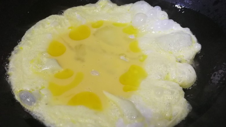 金针菇炒蛋,热锅倒入适量，油热倒入蛋液，煎至蛋液凝固。